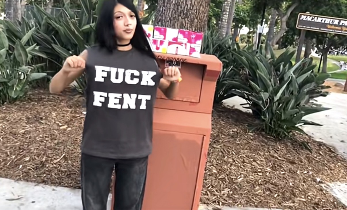 Crystal Tufts in the FUCK FENT shirt next to a Narcan box in MacArthur Park, LA